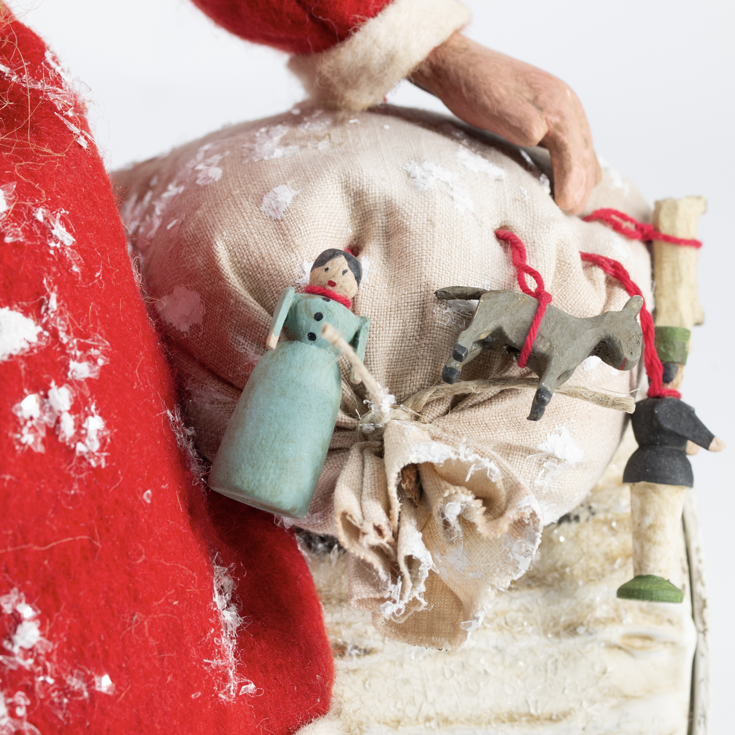 Detail: Hand des Weihnachtsmanns am Sack mit Puppe und Pferd
