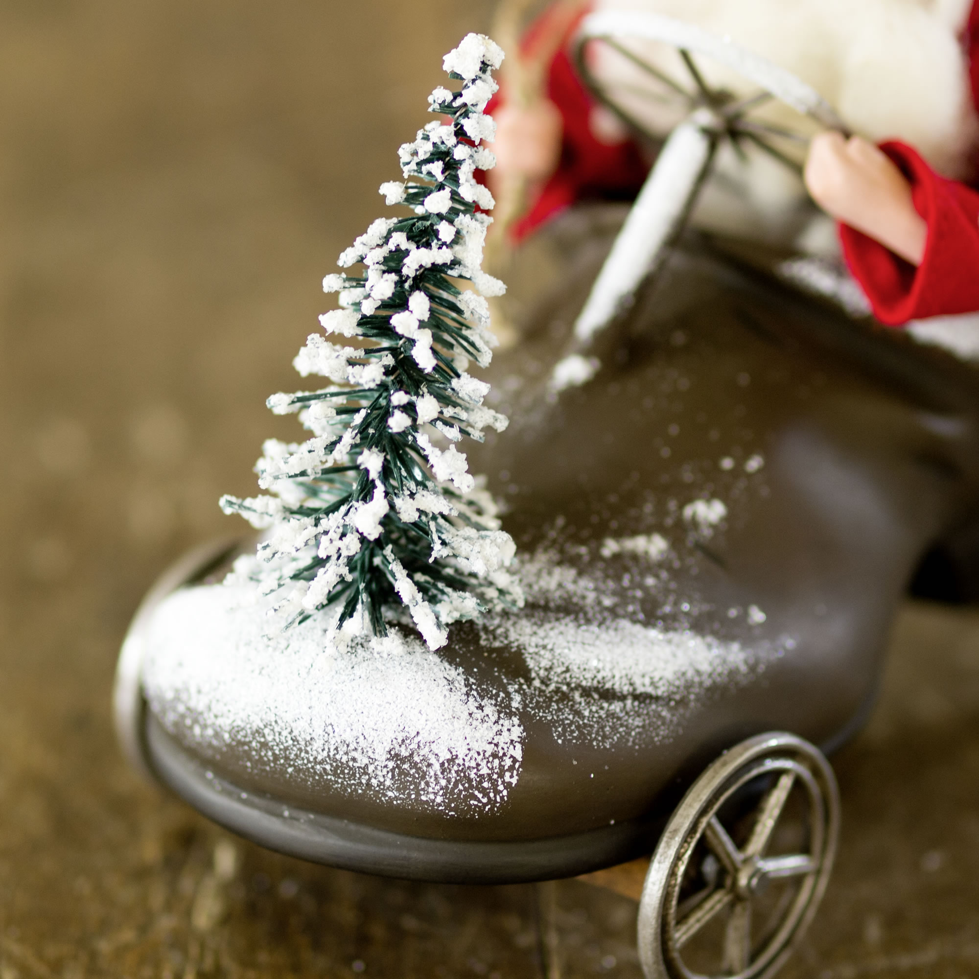 Schneebestäubter Mini-Tannenbaum auf braunem Deko-Fahrzeug