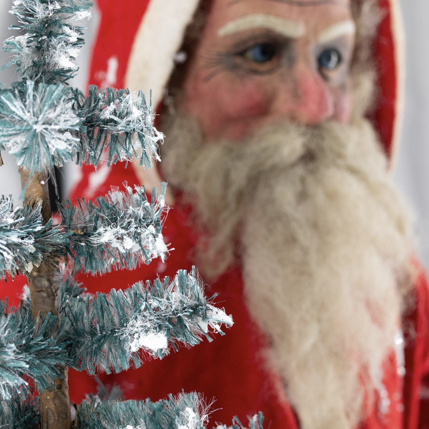 Deko-Tannenbaum mit Kunstschnee vor Weihnachtsmann-Figur