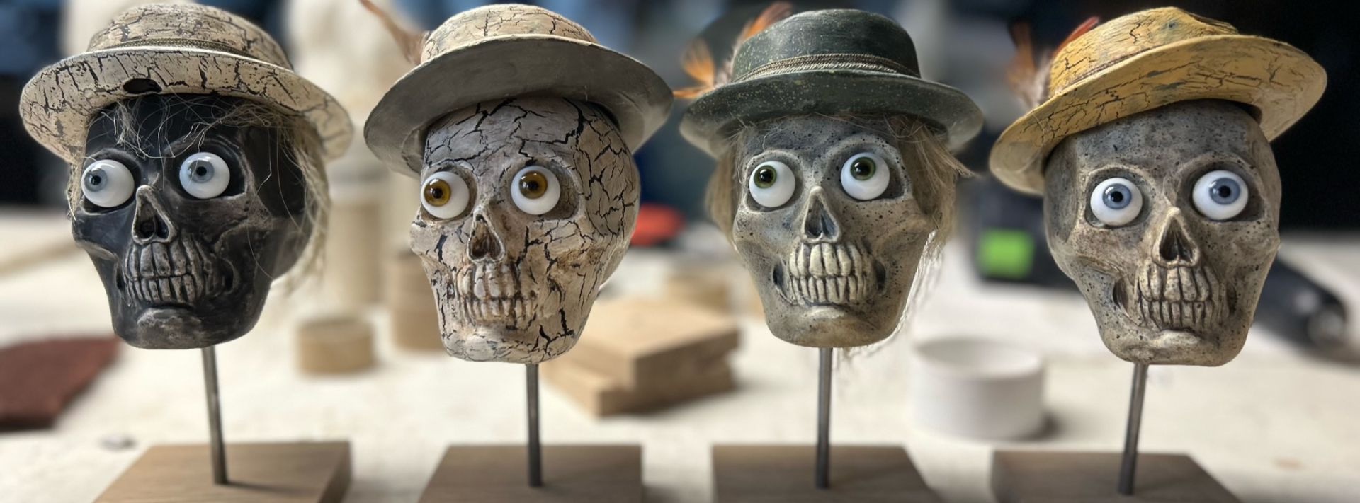 Vier Deko-Schädel mit Hüten auf Ständern, Halloween